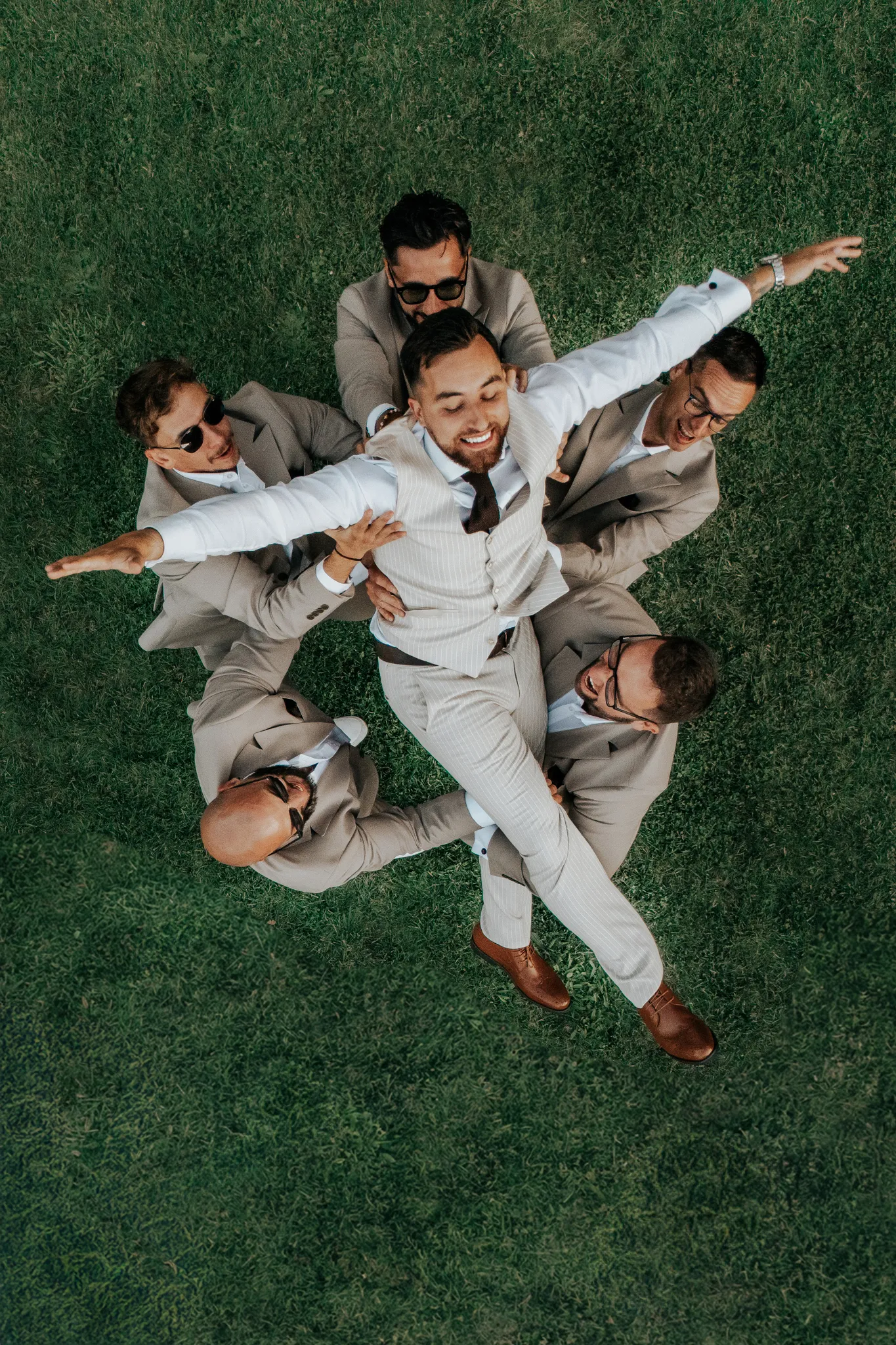 panmlody w powietrzu podrzucany przez radosnych druhow podczas weselnego przyjecia w jednolitych farniturach. ujecie wykonane z drona dji. Fotograf slubny tychy